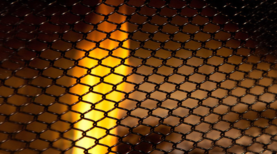 Close-up of a Condar hanging mesh screen with a flame in the background
